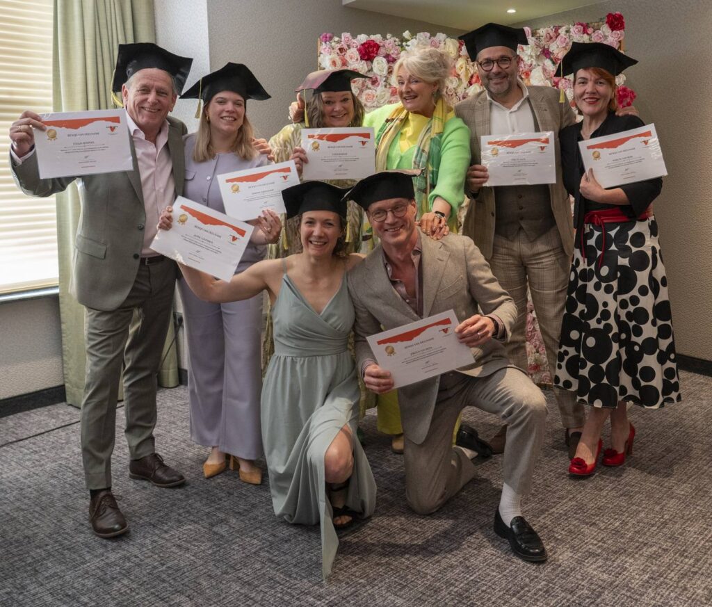 Groep afgestudeerde trouwambtenaren met diploma’s en afstudeerhoedjes